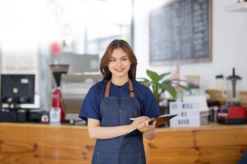 attractive young beautiful asian woman employee or small business owner waitress in an apron...