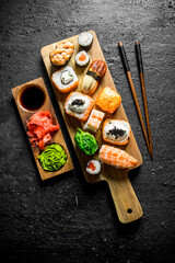 Variants of types of sushi, rolls and maki on a cutting Board with sticks.