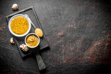 Mustard on a cutting Board with garlic cloves.