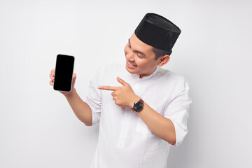 Smiling young Asian Muslim man pointing finger at display mobile phone screen isolated on white background. People religious Islam lifestyle concept. celebration Ramadan and ied Mubarak