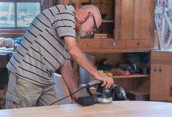Male carpenter, working in the carpenter's workshop with power hand tools.