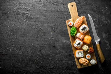 Set of different types of sushi and rolls on wooden cutting Board.