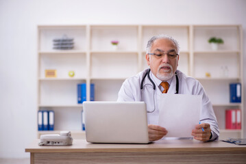 Old male doctor working in the clinic