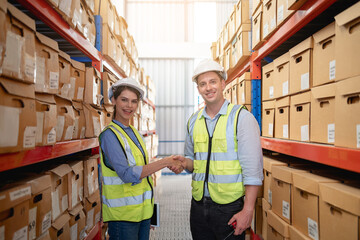 Workers in the warehouse shake hands near the shelves at the manufacturing.