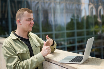 Caucasian man communicates in sign language via video link on laptop. 