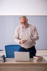 Old male teacher in front of whiteboard