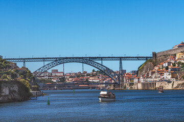 Small boats on the Douro River in Porto with the Luis I Bridge in the background