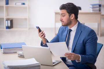 Young male employee and too much work in the office