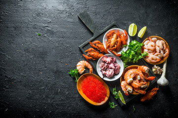 Caviar and seafood on a cutting Board with herbs and lime slices.