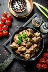 Fried liver with spices and cherry tomatoes on a cutting Board.