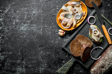 Fillet of salted herring on a piece of bread and onions.