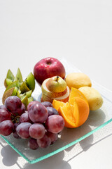Fresh fruits in plate on white table. Acceptable fruits for diabetes. Kiwis,grapes,orange, apples,pears,Healthy diet and low-calorie diet.Healthy vegetarian food. copy space