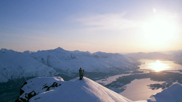 A panoramic view of a snowboarder on top of a mountain in Valdez, Alaska