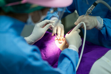 Dentist with an assistant in protective gloves are examining her teeth with a help of a dental bur with a mirror and an air polisher. Caries healing. Examination of the dentist.