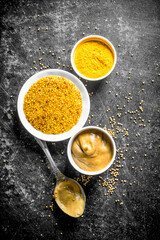 Different types of mustard with a spoon.