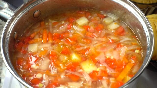 Vegetable soup cooks in a pan.