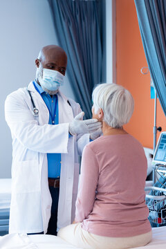 Vertical Of Diverse Senior Male Doctor Examining The Throat Of Senior Female Patient, Copy Space