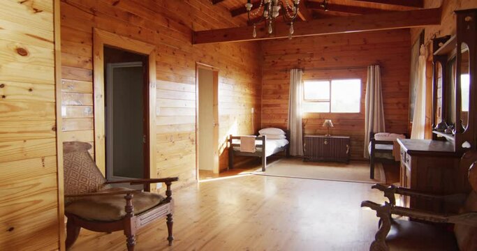 General view of bedroom with beds and armchairs in log cabin, slow motion