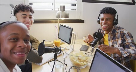 Portrait of happy diverse male teenage friends using laptop and recording podcast, slow motion - Powered by Adobe