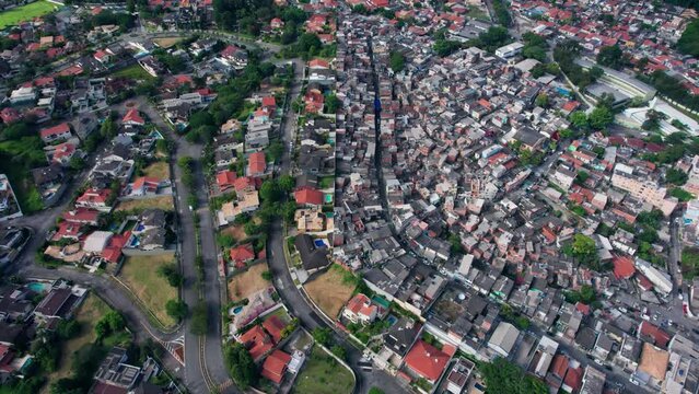 Two Contrasting Residential Neighborhoods in Sao Paolo, Brazil. Wealthy Gated Neighborhood next to impoverished Favelas. separated by a Wall.  Gimbal overhead ascending shot.