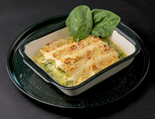 Lasagna with spinach. Homemade Italian lasagna with spinach chicken. Dark background.