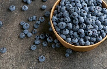 Fresh blueberries with water drops in a wooden bowl. View from above.