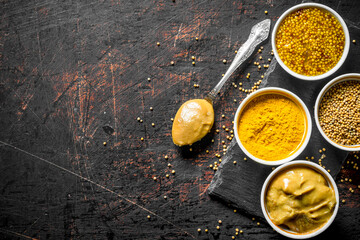 Different types of mustard on a stone Board with a spoon. - 562923973