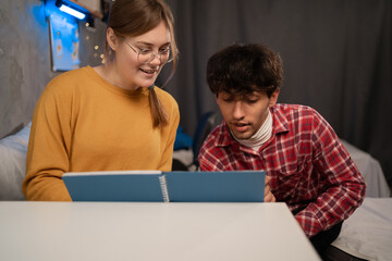 College student asking girlfriend to help his with math homework, education in dormitory room.