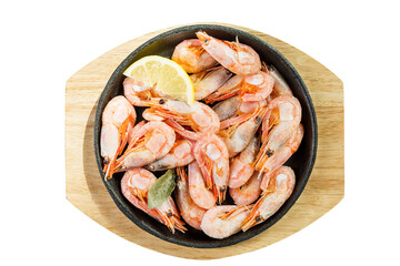 Boiled shrimp with lemon in a portion pan on a wooden board. Appetizing snack. Top view. Close-up. Isolated on white background.