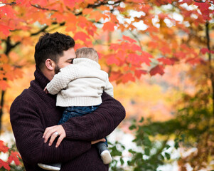 Loving father embracing son while carrying him at park during autumn