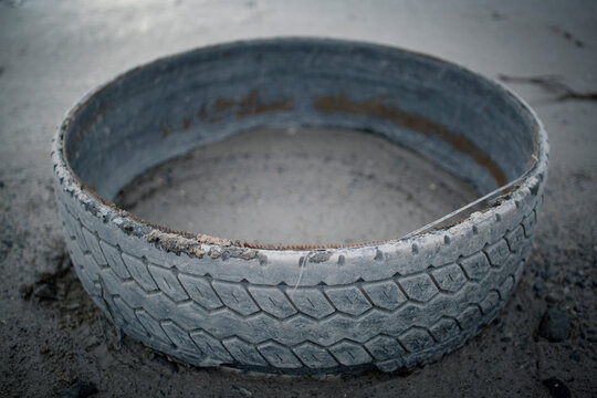 The rim of an abandoned tire sits in the mud.