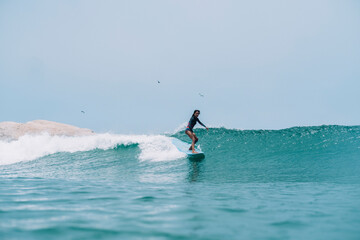 Pulled back view of a female surfer on a wave