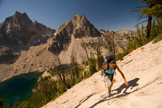 A young woman hikes up a steep hill above Warbonnet Lakes in the Sawtooth Mountains, Idaho.