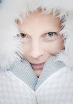 Close up of a woman clutching a white fur hoody and grinning.