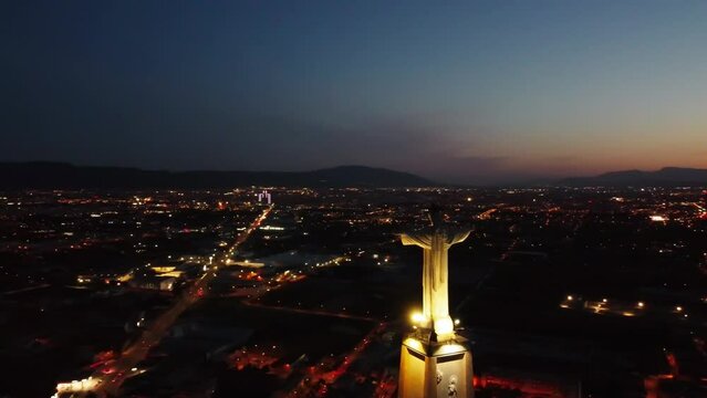 Aerial drone view of Monteagudo Christ castle at night against  sunset and Murcia cityscape in Spain. Replica  of the Christ located on the top of the Concorvado Mountain in Rio de Janeiro dron shot.