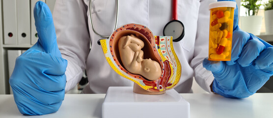 Gynecologist recommends vitamins for baby fetus and holds thumbs up