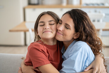 Friendly happy woman and teen girl hug and rejoice at meeting after long separation or going on...