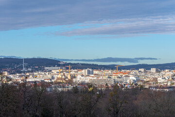 Fototapeta na wymiar Austrian city of Vienna, panorama from a height, city buildings and mountains, blue sky.