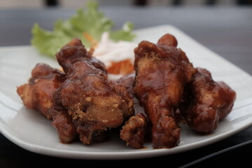 brown spicy chicken drumstick with mayo salad on white plate
