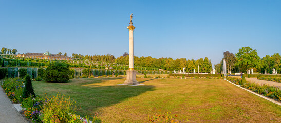 Obraz premium Panoramic view over garden, pools, flowers, old statues, fountains and many tourists in the city park of Potsdam, a German town of statues and sculptures, Germany, at sunny summer day