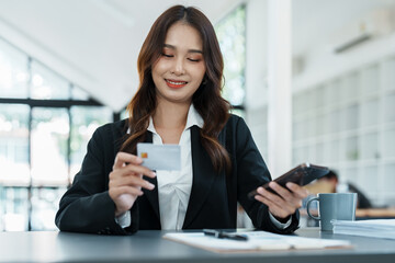 Obraz premium Online Shopping and Internet Payments, Asian woman are using their credit card and mobile phone to shop online or conduct errands in the digital world.
