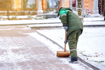 Man clear snow from sidewalk, cleans footpath from snow during blizzard. Utility worker shoveling...