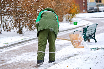 Man clear snow with shovel from sidewalk during snow storm, cleans footpath from snow during...