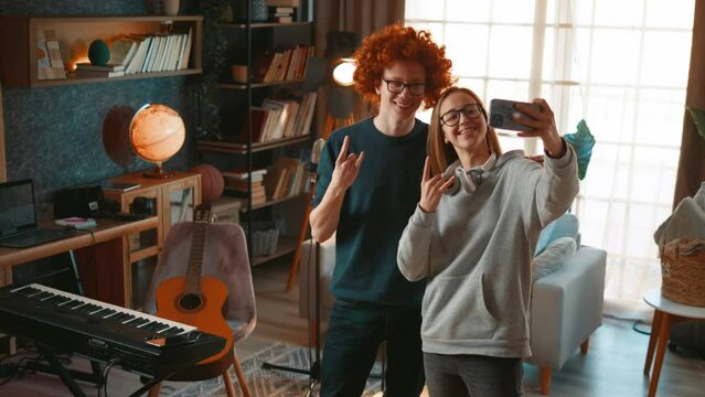Teenage musicians boy and girl taking a selfie photo in their home studio or sending video messages.
