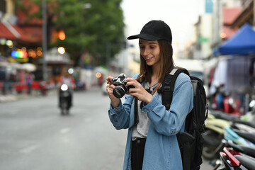 Caucasian woman tourist photographer with camera standing in busy city street in Chiang Mai Northern Thailand