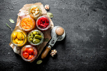 Jars of preserved vegetables on paper.