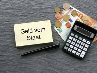 Euroscheine und Taschenrechner mit dem Text Geld vom Staat auf einem Notizblock. - obrazy, fototapety, plakaty