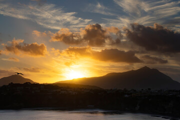 Houses of Procida in magic sunset with the island of Ischia in the background.