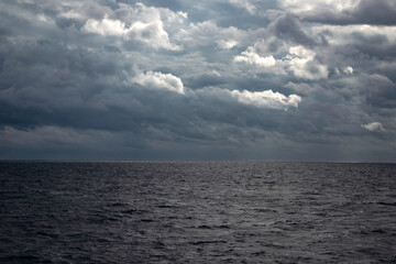 Obraz premium Sea with dramatic rainy clouds and sun beams.
