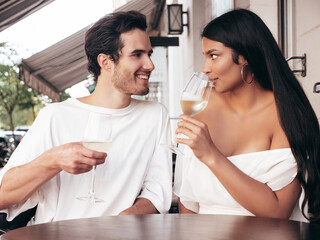 Smiling beautiful woman and her handsome boyfriend. Happy cheerful family. Sexy couple cheering with glasses of red wine at their date in restaurant. Drinking alcohol at veranda cafe